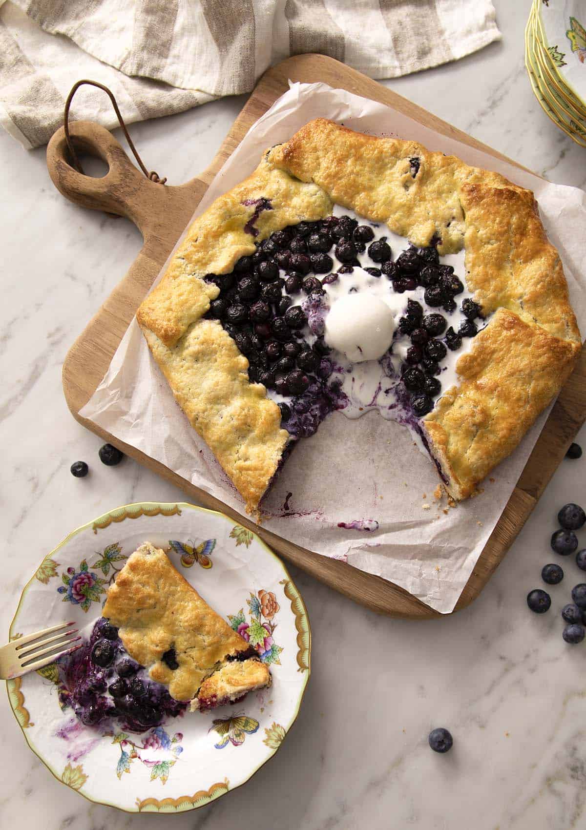 A blueberry galette with a piece removed and on a plate.