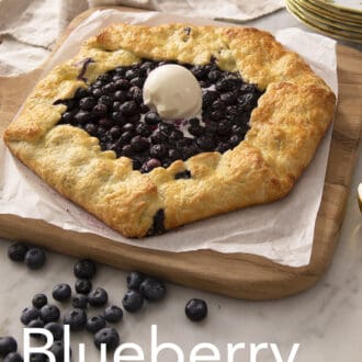 A blueberry galette on a wooden board next to an ice cream scoop.