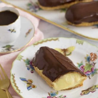 Pinterest graphic of an eclair on a plate with coffee and more eclairs in the background.