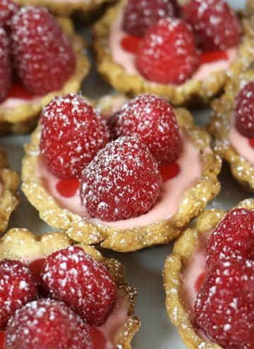 a group of small raspberry tarts dusted with powdered sugar