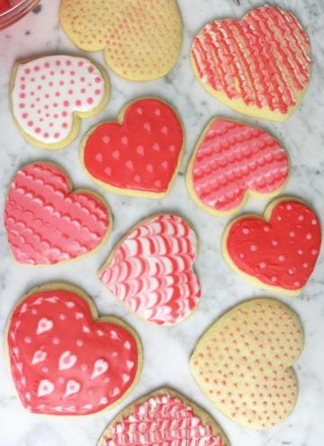 Overhead view of multiple Valentine's day sugar cookies decorated in various ways.