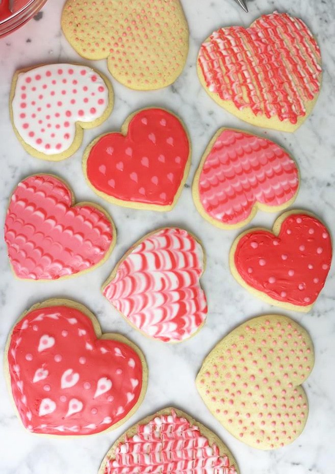Overhead view of multiple Valentine's day sugar cookies decorated in various ways.