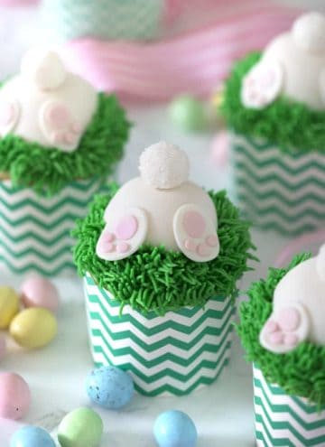 A photo of bunny butt cupcakes with chocolate eggs around them.