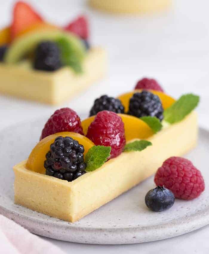 A photo showing a rectangular fruit tart on a gray plate.
