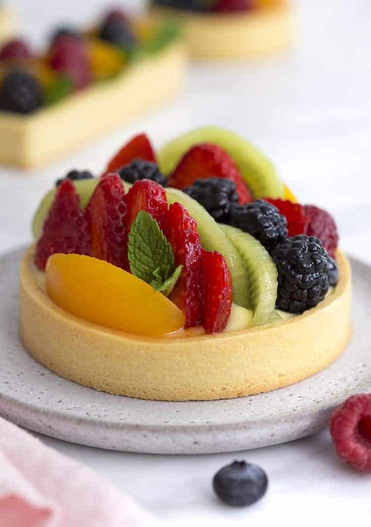 A photo of a fruit tart with various berries, peach slices and kiwis.