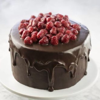 a chocolate raspberry cake on a white cake stand