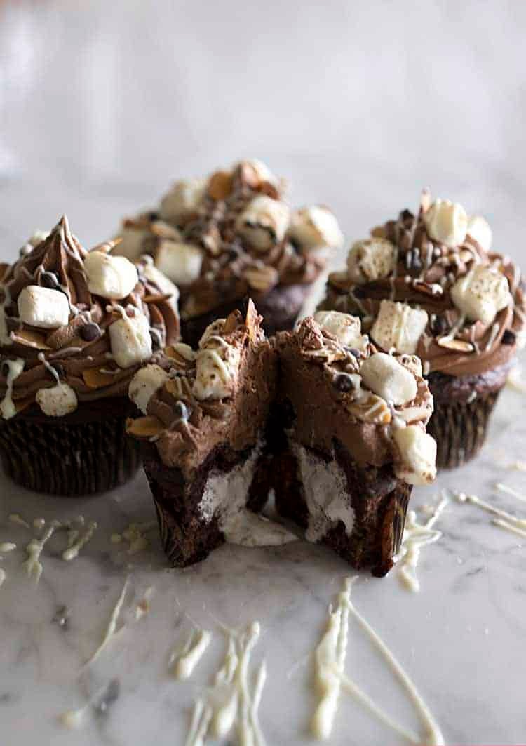 A group of rocky road cupcakes with one cut open showing a marshmallow interior