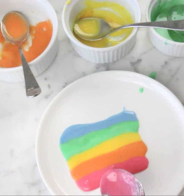 Different colored glazes lined up in a rainbow on a plate