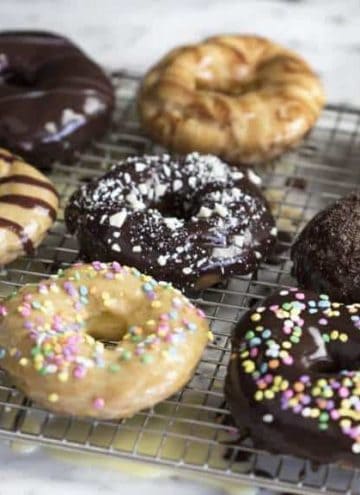 A photo of Chocolate Eclair Donuts on a cooling rack.