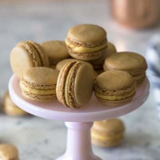 pumpkin macarons on a pink tray