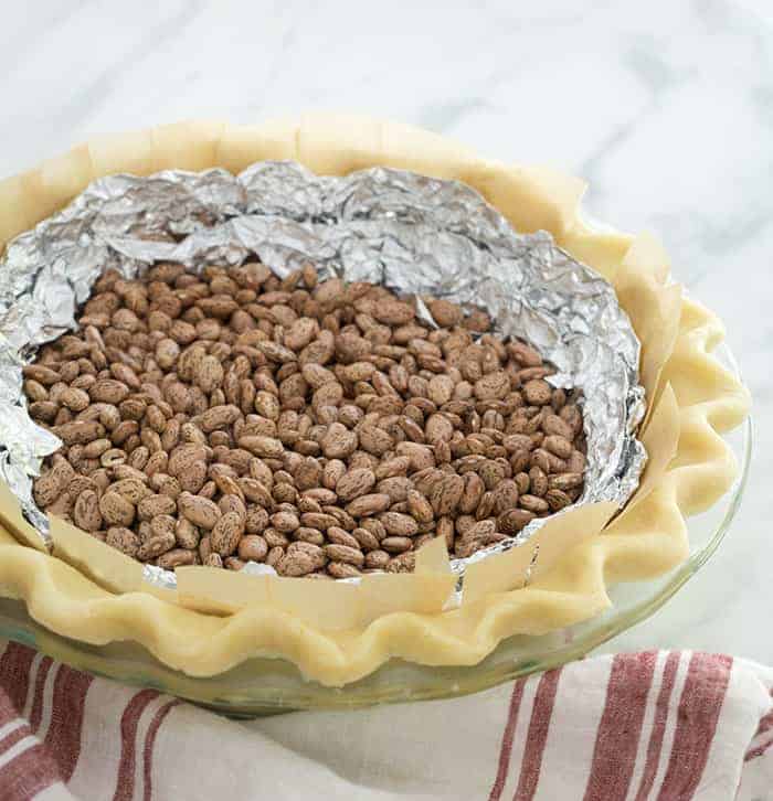 An unbaked pie crust filled with foil and beans