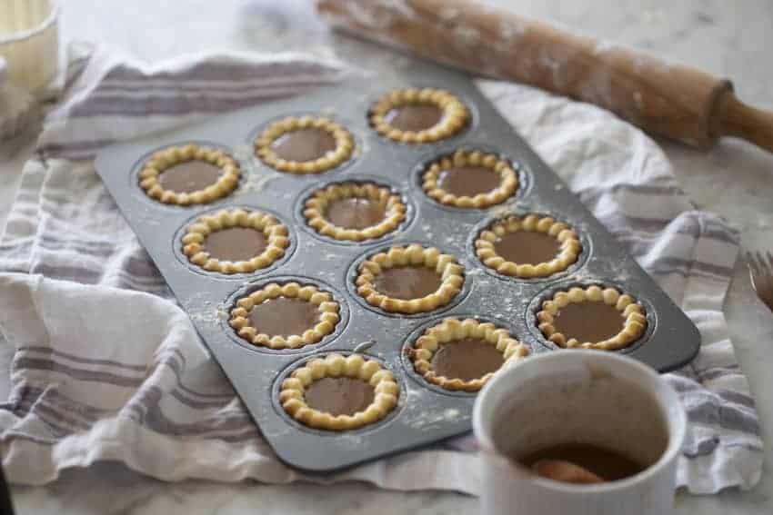 A photo of Rose Apple Tart shells filled on a table.