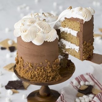 A slice of s'mores cake being lifted from the cake on a cake stand.