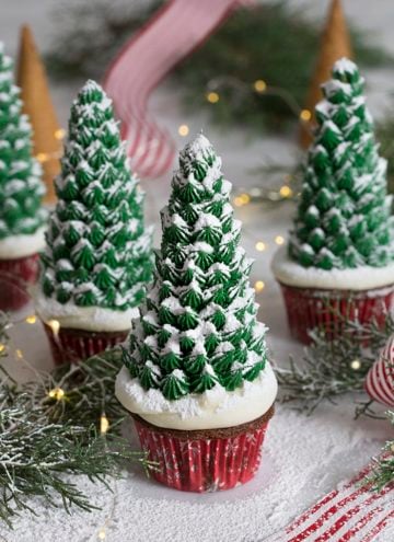 A photo of a group of Christmas tree cupcakes surrounded by pine needles.
