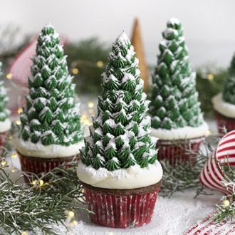 A photo of three Christmas tree cupcakes on a white marble table.
