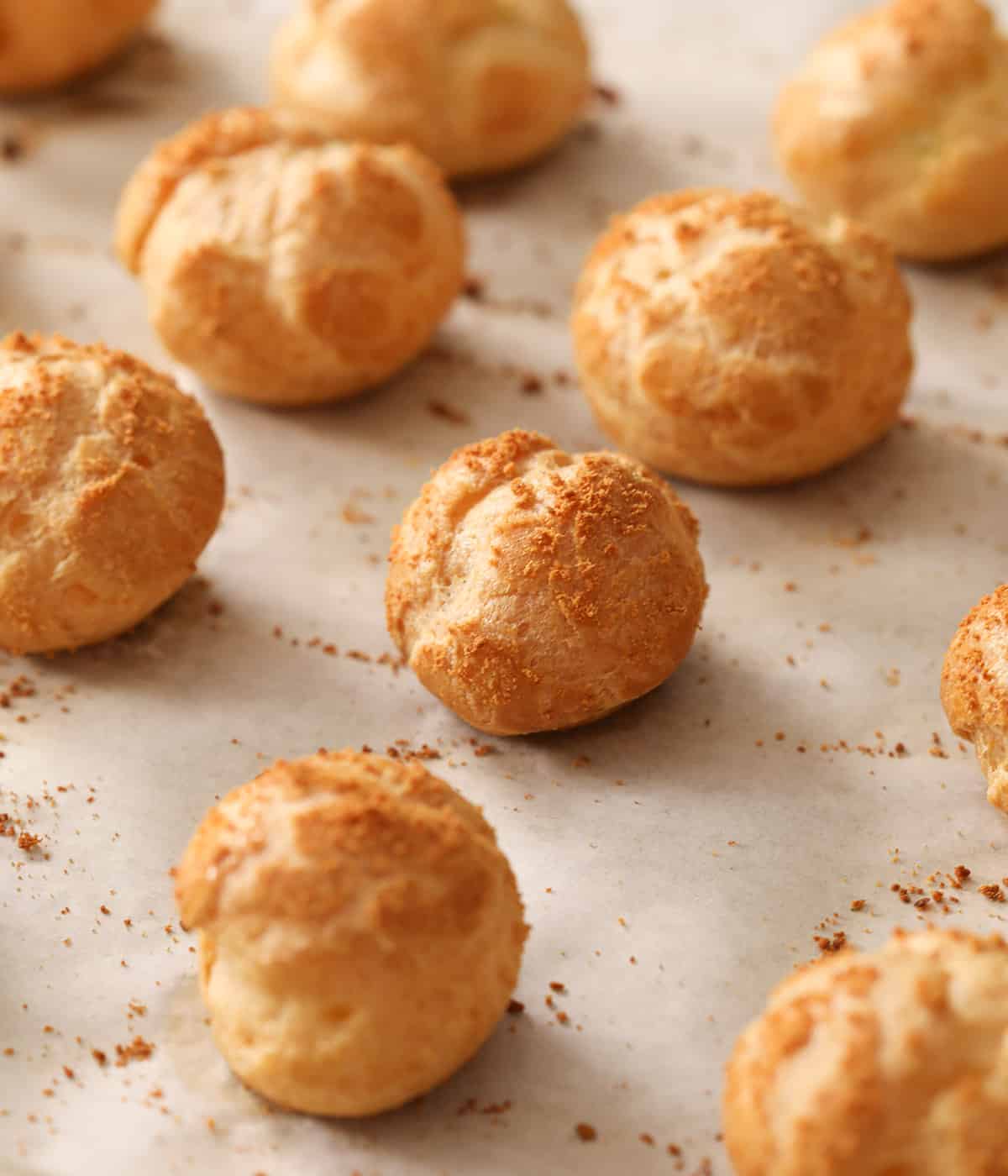 Choux puffs cooling on a baking sheet.