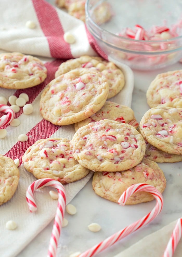 A photo of white chocolate peppermint cookies on a marble table surrounded by candy canes