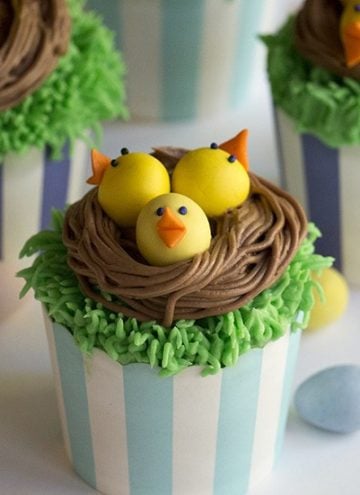 A photo showing cupcakes with baby chicks in a chocolate nest on top.