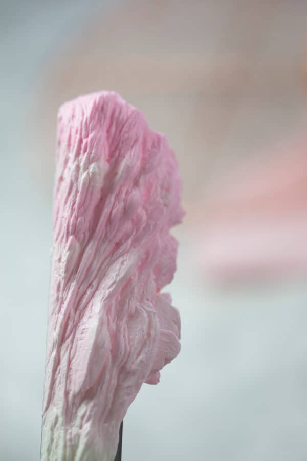 A photo showing an ombré of pink Italian buttercream on an offset spatula.