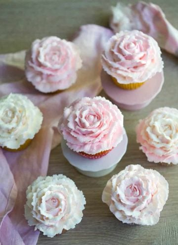 Multiple rose cupcakes with two on mini cupcake stands.