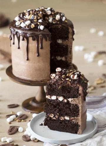 A Rocky Road Cake with a piece in the foreground on a small plate.