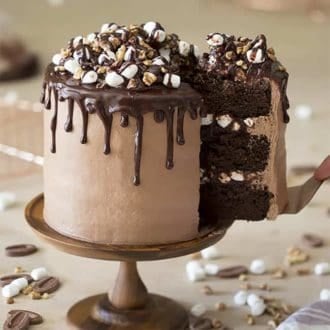A Rocky Road Cake on a wooden cake stand with a lift lifted out.