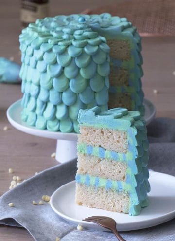 An aqua and seafoam green petaled mermaid cake with a piece in the foreground