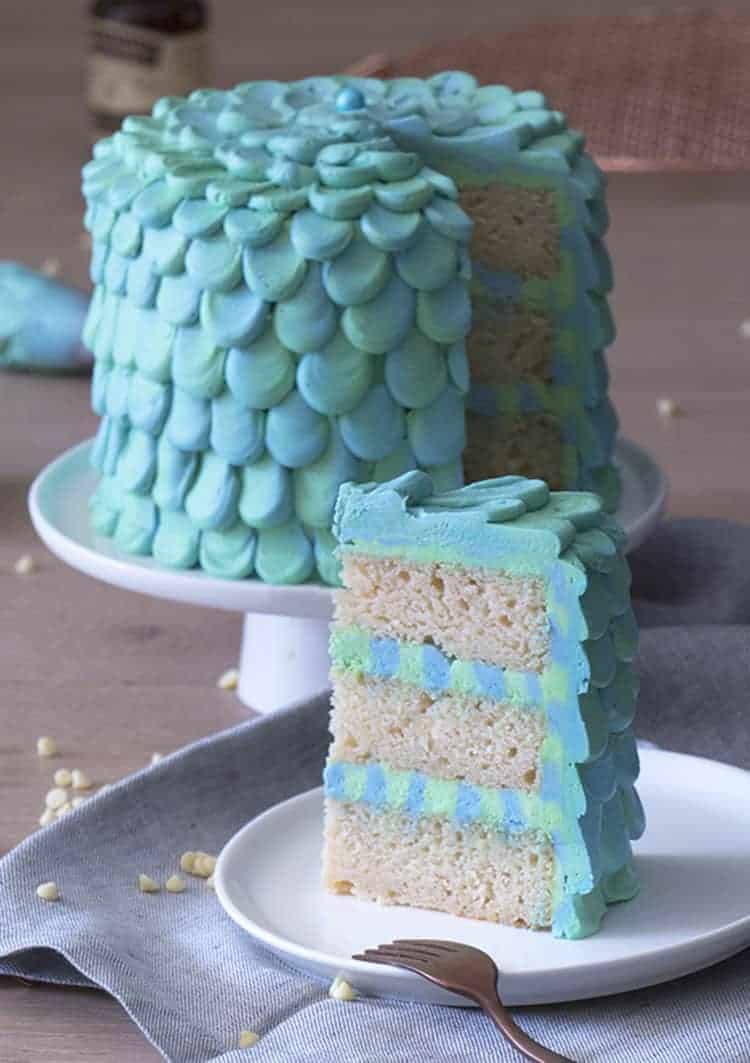An aqua and seafoam green petaled mermaid cake with a piece in the foreground