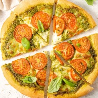 An overhead shot of a pesto pizza cut into slices