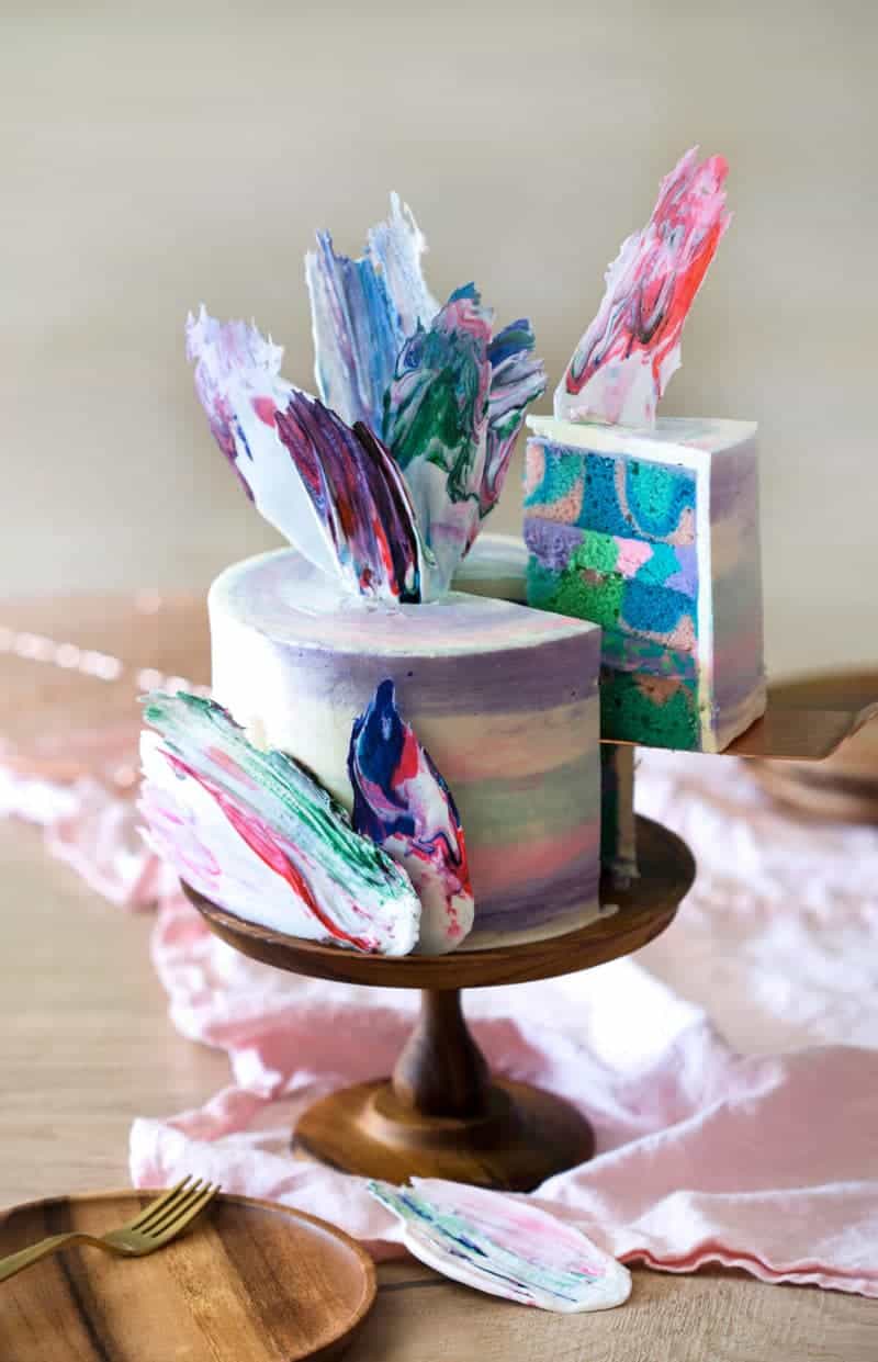 photo of a rainbow Cake on a wooden cake stand