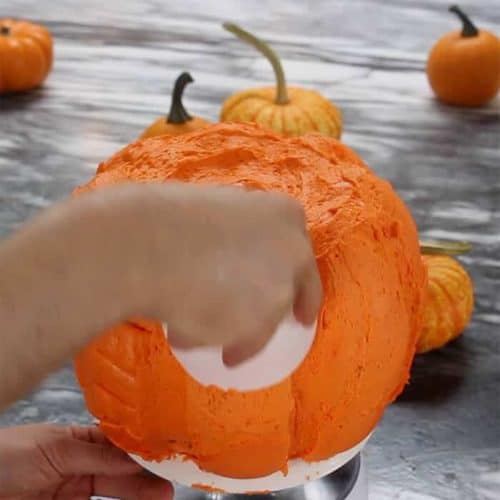 Frosting spread onto a pumpkin bundt cake.