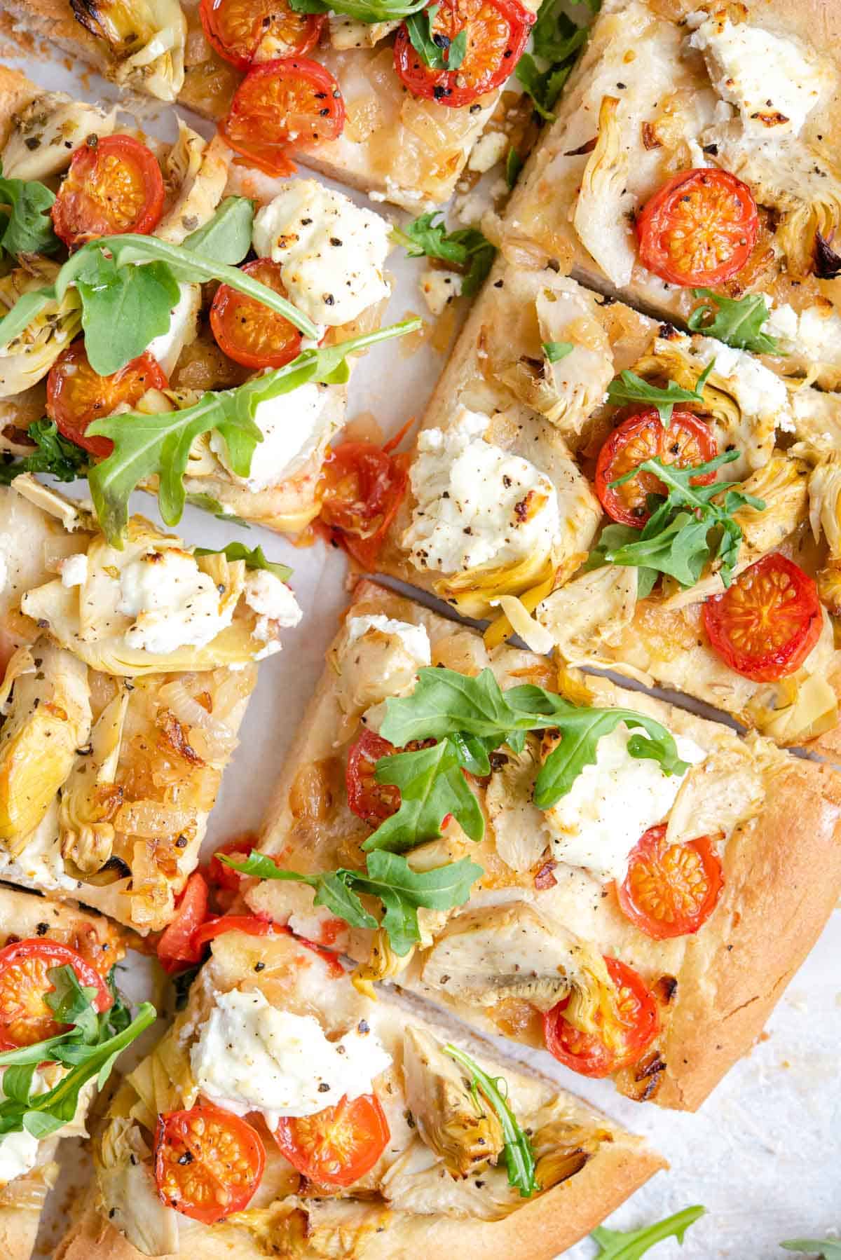 An overhead shot of an artichoke pizza cut into slices