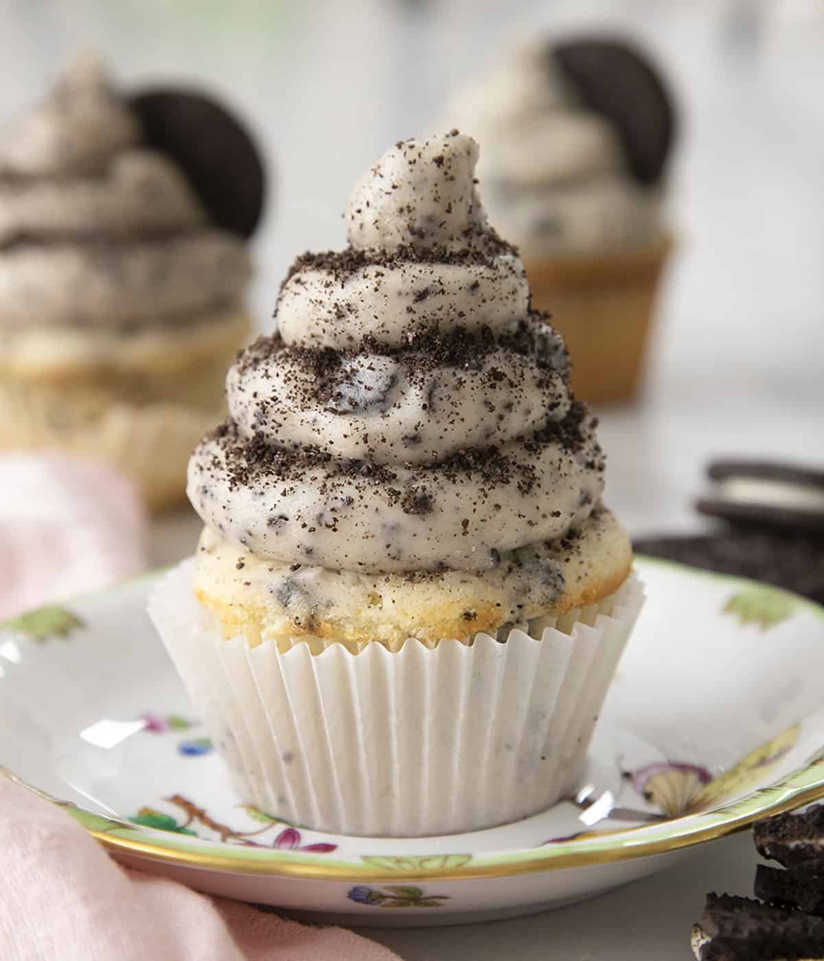 An Oreo cupcake topped with a nice swirl of Oreo buttercream on a plate.