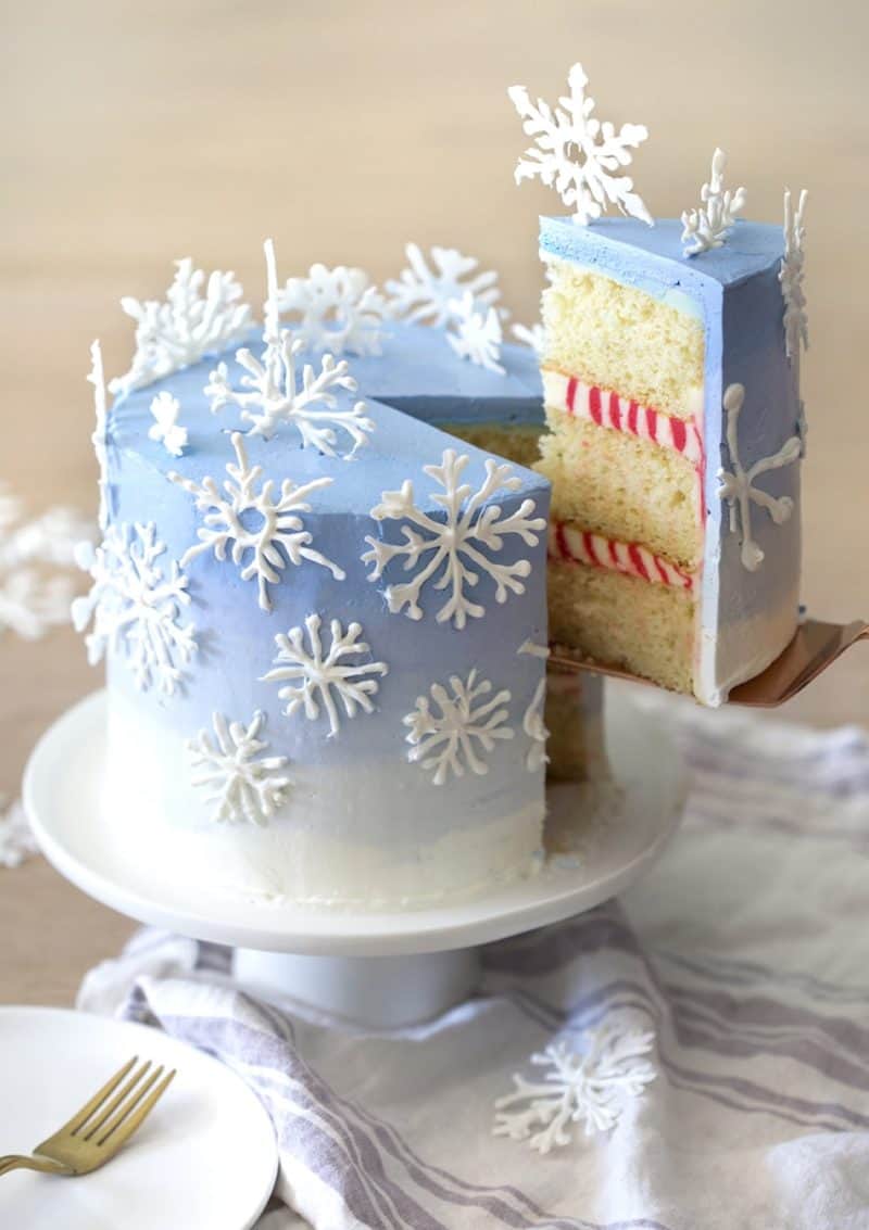 A photo of a piece being removed from a cake with snowflakes on top.