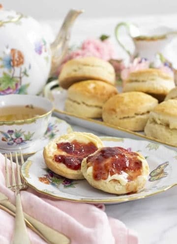 scones on a porcelain plate with a teapot next to them