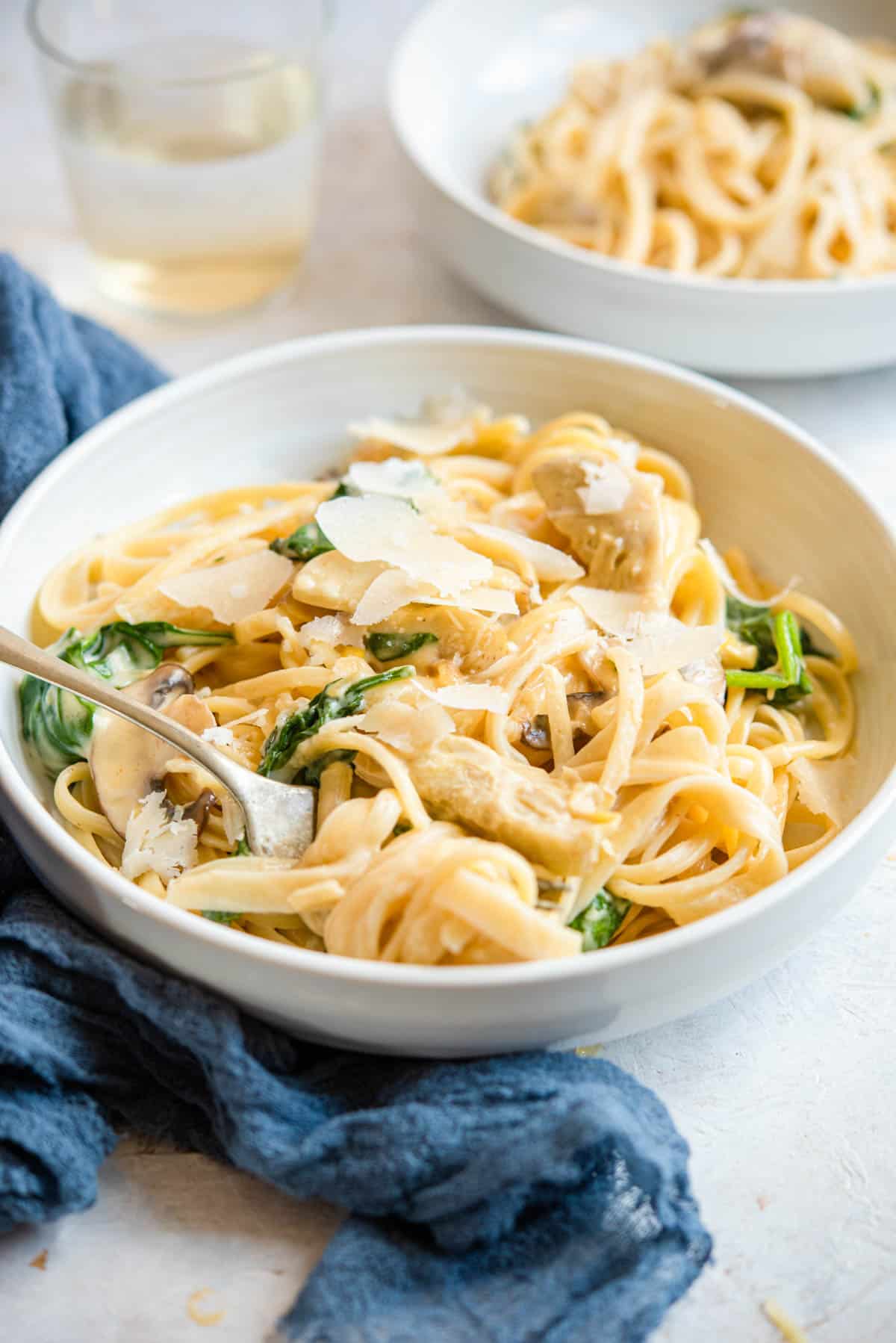 A side shot of artichoke pasta in a bowl with a fork