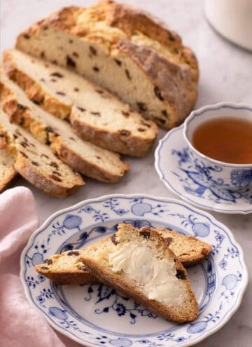 Slices of Irish soda bread spread with butter on a blue plate.