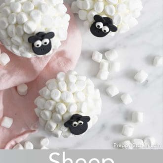 Pinterest graphic of an overhead view of three sheep cupcakes. Multiple mini marshmallows scattered around with a pink napkin.