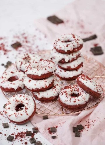 A photo of a group of Red Velvet Donuts on a copper cooling rack with a light pink linen underneath