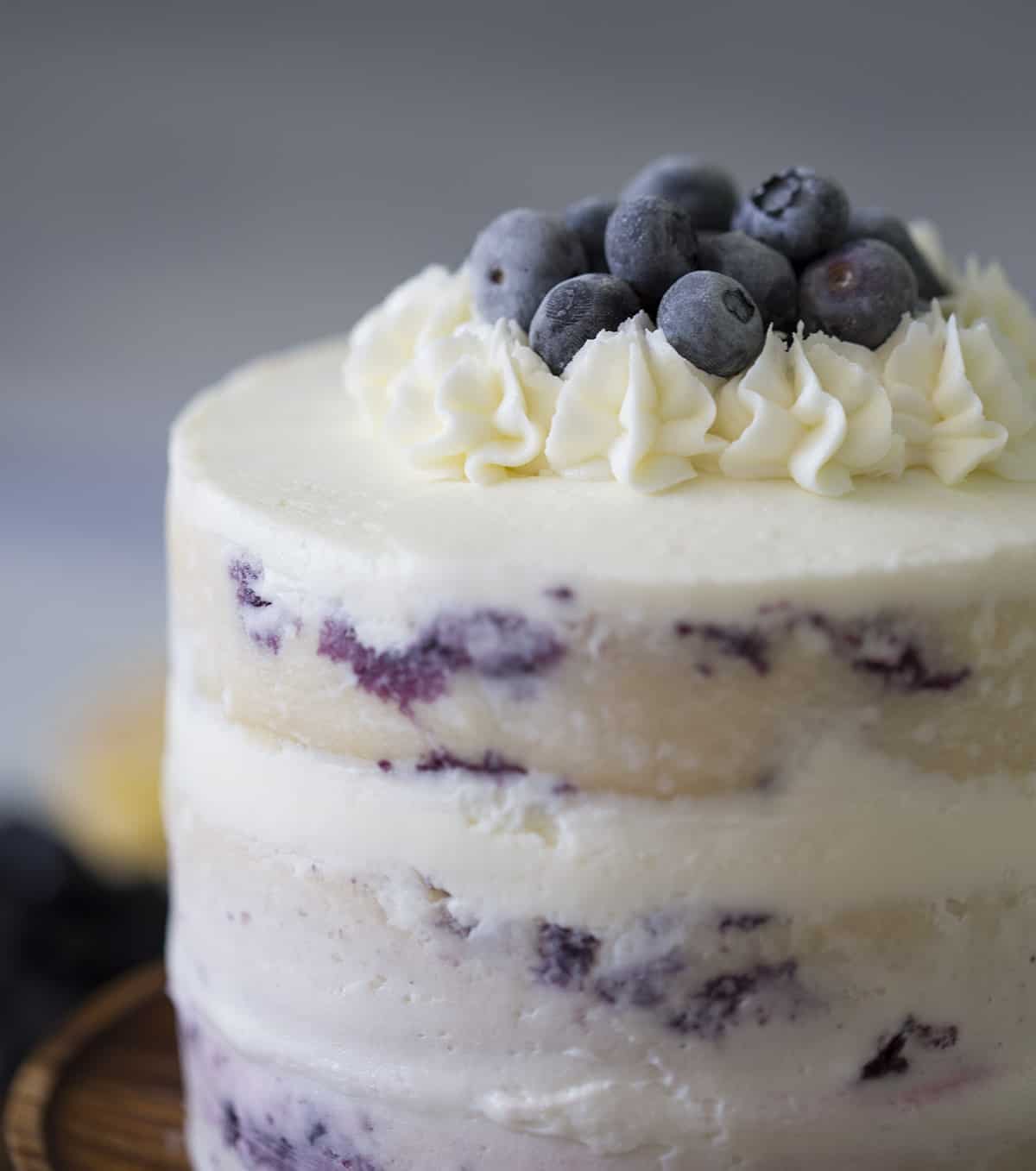 A layered lemon blueberry cake topped with blueberries.