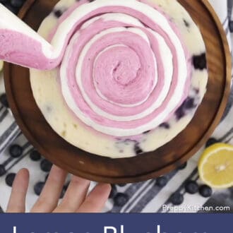 frosting being added to three layered lemon blueberry cake with white frosting