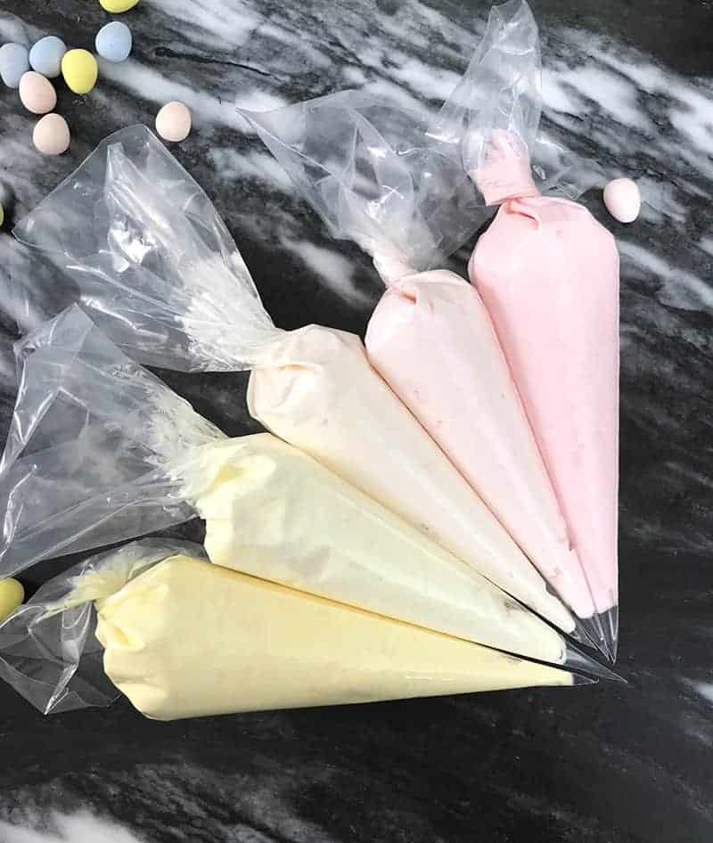 A photo of different colored buttercreams in piping bags.
