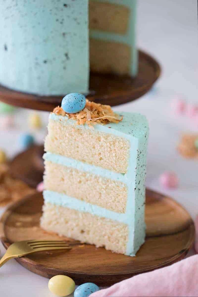 An easter egg cake piece on a wooden plate.