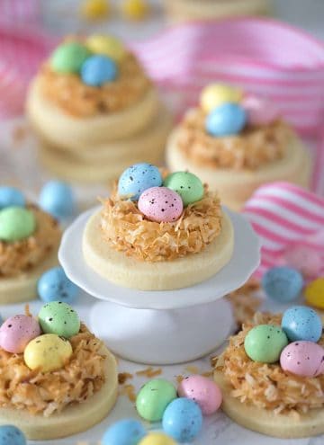 round sugar cookies topped with nests made with toasted coconut and candy eggs