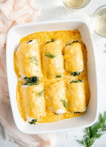 An overhead shot of baked fillet of sole in a baking dish with a cheese sauce