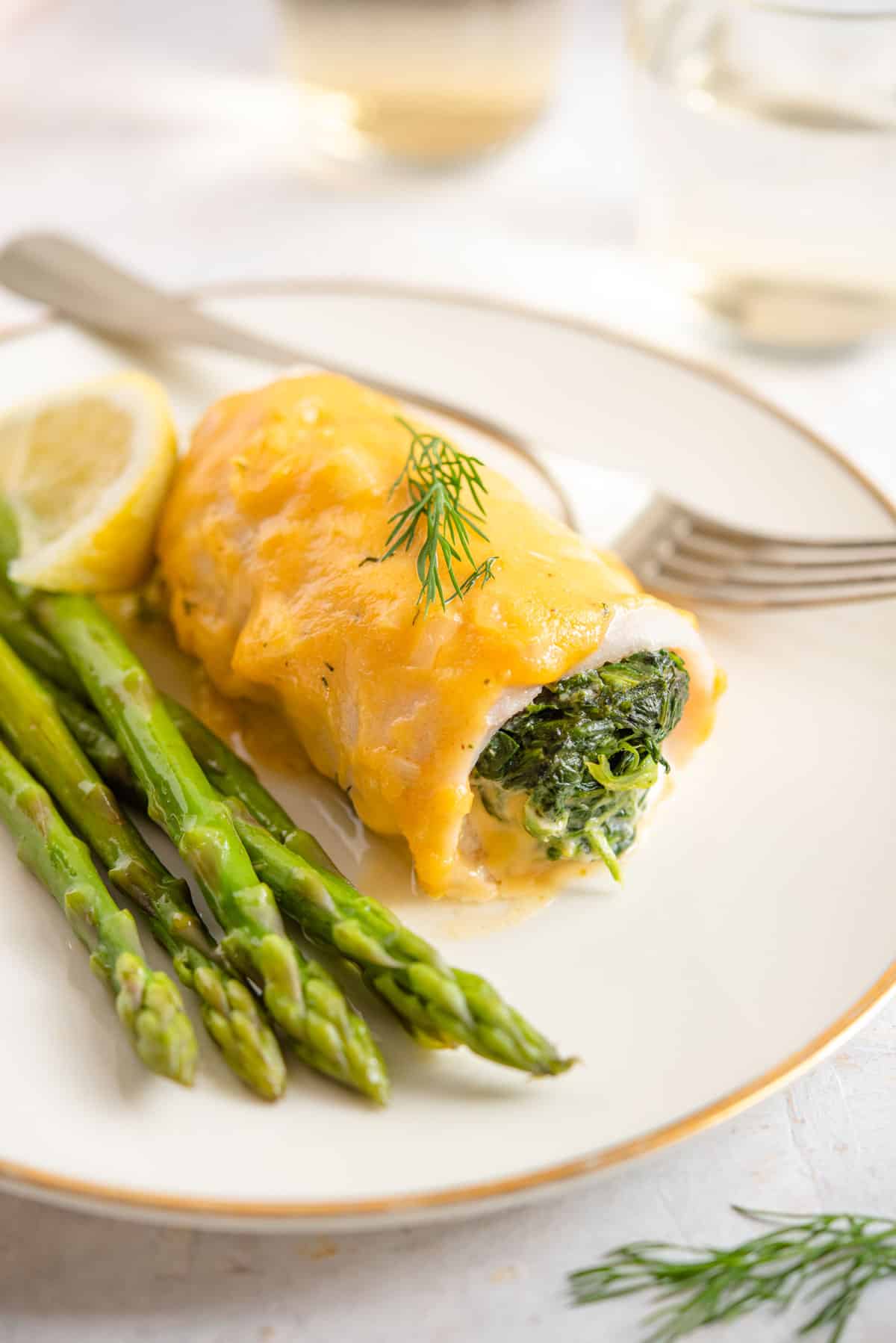 A close up of stuffed fillet of sole with a cheese sauce on a plate
