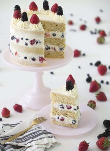 Photo of a Berry Cake cake on a pink cake stand with a piece on a plate