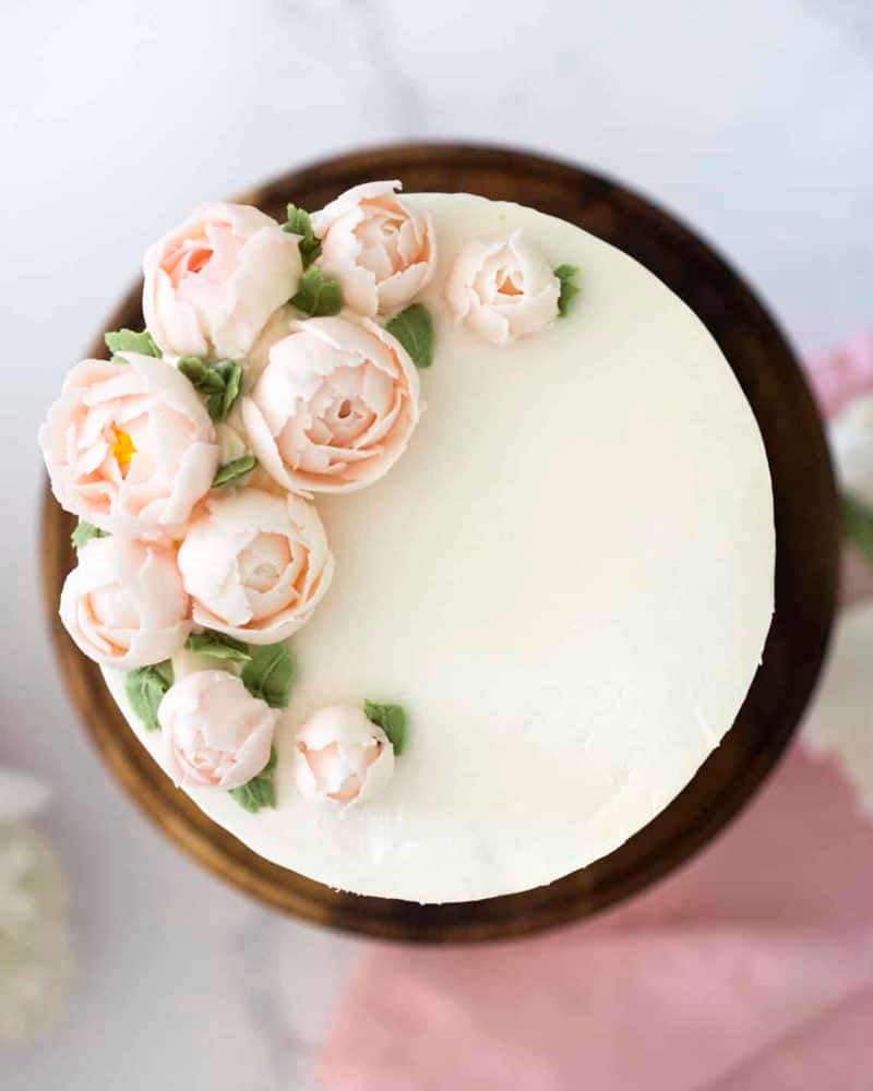 Top Down view of a lemon elderflower cake with soft pink buttercream peonies