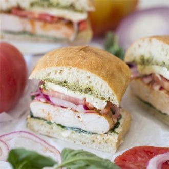 Photo of half a chicken sandwich with basil and tomatoes