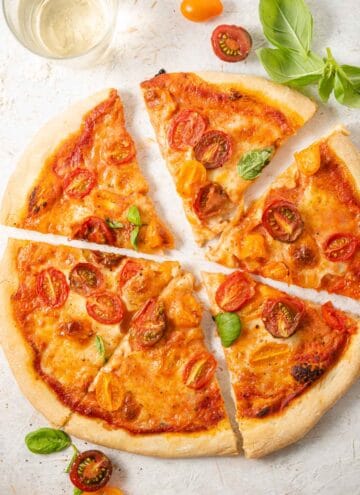 An overhead shot of a tomato pizza cut into slices